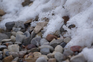 Multicoloured pebbles with patch of snow on it, macro