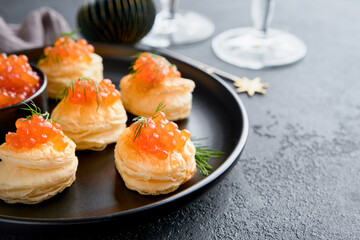 Salmon red caviar toast. Christmas canape or toast with red caviar on black plate on dark background. Idea to xmas snack. Gourmet food. Texture of caviar. Seafood.