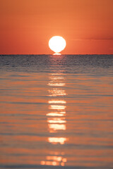 Tramonto sul mare con il riflesso del sole sull'acqua.