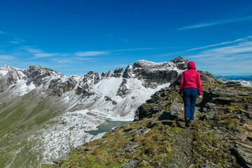 Fototapeta premium Hiker woman with scenic view of majestic mountain peaks of High Tauern seen from Feldseekopf, Carinthia Salzburg, Austria. Idyllic hiking trail in Goldberg group in remote Austrian Alps. Wanderlust