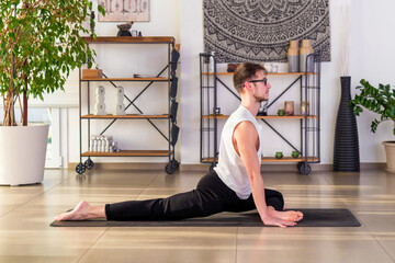 Young man doing Half Pigeon yoga pose on mat