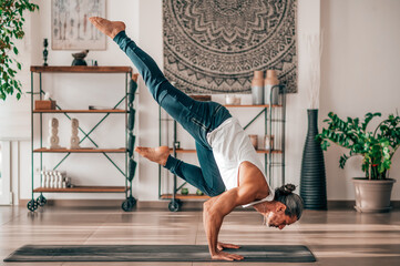 Flexible man performing Flying Crow asana at home