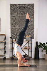 Fit man performing supported handstand yoga at home