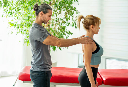 Male osteopath performing postural evaluation on female patient