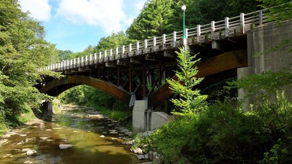 Fototapeta na wymiar Arched bridge crossing gentle creek in countryside America New York State