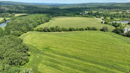 Country roads in rural New York State with green fields, trees and rivers and gently rolling hills