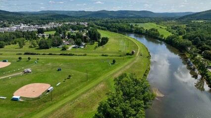 Peaceful countryside landscape in Olean, NY with river, hills, green pastures under blue sky and clouds