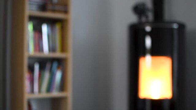 Blurred pellet stove in a living room with bookcase and heat diffuser