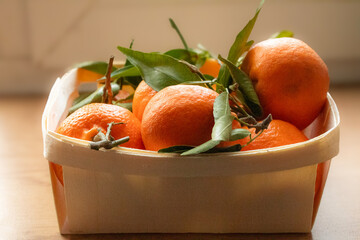 tangerines with green leaves in a wooden box
