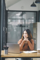 Fototapeta premium Beautiful young concentrated business woman wearing shirt using laptop while standing in modern workspace