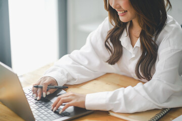 Beautiful young concentrated business woman wearing shirt using laptop while standing in modern...