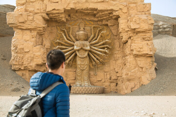 Silk Road Heritage City, Dunhuang City, Gansu Province - People standing in front of Buddha statues