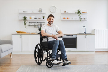 Full length portrait of Caucasian wheelchair user smiling at camera while resting in open-plan...