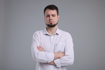 Portrait of sad man with crossed arms on grey background