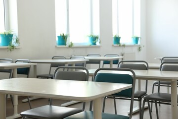 Empty school classroom with desks, windows and chairs