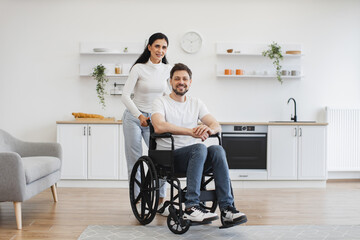 Full length portrait of Caucasian wheelchair user and his wife smiling at camera while resting in...