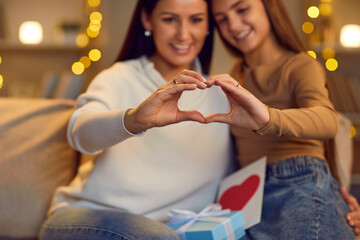 Happy family making heart shape with hands. Mother and child form heart sign with fingers. Mom and daughter cherish tender feelings, appreciate and value each other. Love, care concept background