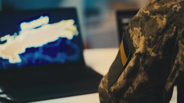 Ukrainian soldier studies intelligence data about Russia on laptop, war strategy