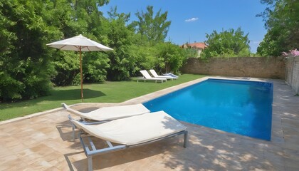 Swim pool with clear blue water and two sun bed on sunny day in a yard