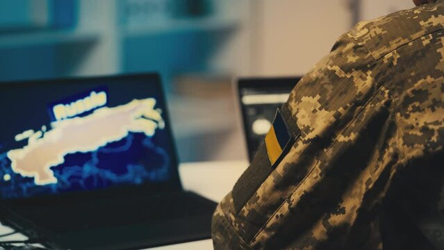 Ukrainian serviceman working in office, Russia map on computer, security data