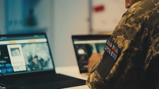 British soldier analyzing satellite data on laptop, studying military targets