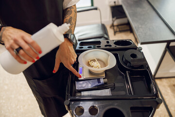 Close up of stylist preparing a hair dye in a container. Hairdresser salon concept
