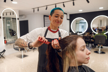 Smiling professional beauty master combing wet hair of a client in a beauty salon