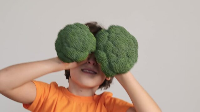 A child's playful curiosity is captured as they hold broccoli like binoculars, a fun introduction to healthy food choices. This playful moment connects with the joy of exploring nutritious options.