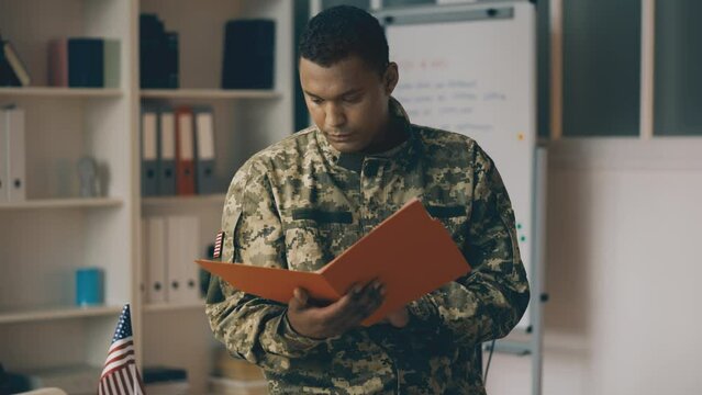 African American cadet reading document in folder, military career, education