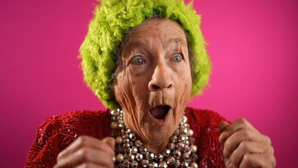 Smiling happy fisheye view of successful funny elderly woman with no teeth and green wig or hat...