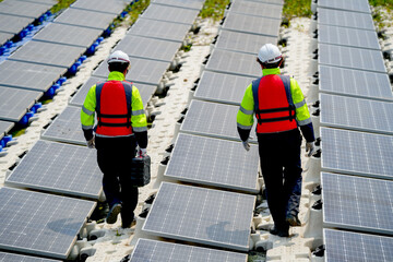 Back of professional with safety uniform walk on footpath along row of solar cell panels in...