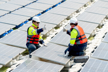 Two technician workers sit together during work with solar panels over water reservoir and show...