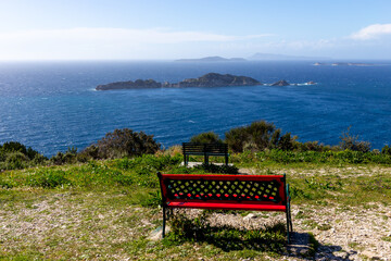 Naklejka na ściany i meble Red bench on the coast of the sea - Corfu, Greece