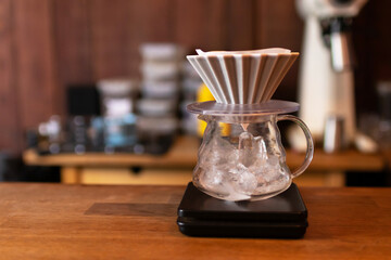 Barista prepare a drip on ice coffee; pour hot water on roasted coffee ground in a filter through on ice.