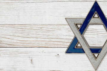 Jewish background with silver and blue star of David on weathered white wood