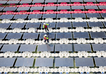 Obraz premium Wide shot of top view two technician workers stand and check to maintenance solar cell panels over the water reservoir as solar farm factory in concept of green energy for good environment.