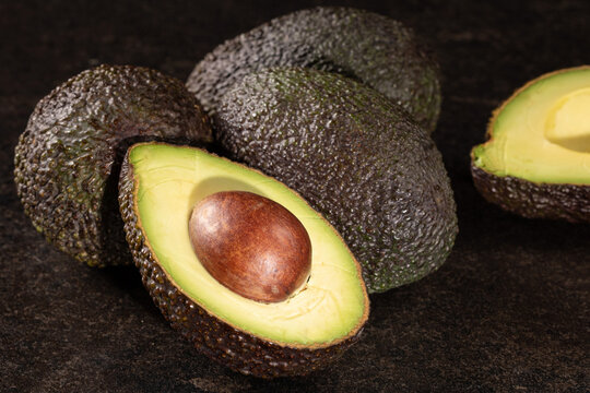 Avocado Halves on Black Stone Table. Healthy Fats Concept. Close-Up Shot.