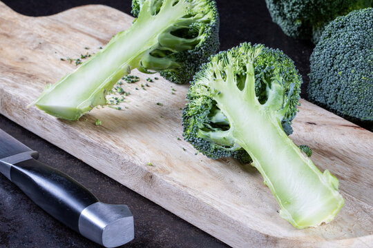 Fresh green broccoli florets on a wooden cutting board with a knife