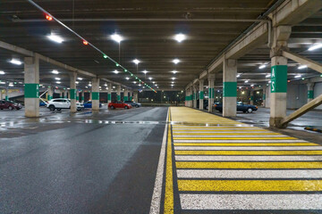 Covered parking for cars. Underground parking. Road markings on wet asphalt. Pedestrian crossing, zebra crossing. Selective focus, blurred background.