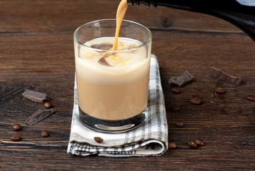 Pouring the original Irish cream liqueur into a glass with ice.