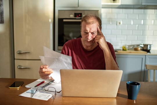 Stressed man going over bills at home