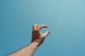 man hand gesturing and reaching the blue sky