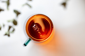 A glass cup of fresh black tea on a white table