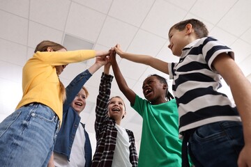 Happy children giving high five at school, low angle view