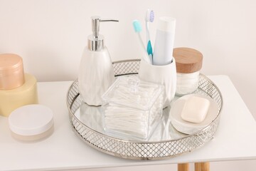 Different bath accessories and personal care products on table near white wall