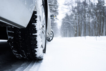 Car with winter tires on snowy road in forest, closeup. Space for text