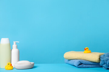 Baby cosmetic products, bath ducks, sponge and towels on light blue background. Space for text