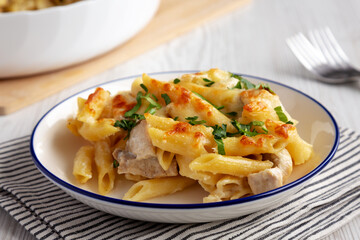 Homemade Cheesy Chicken Alfredo Pasta Bake on a Plate, side view. Close-up.