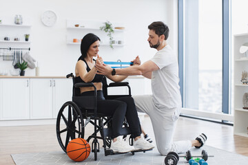 Concept of rehabilitation of disabled people. Physiotherapist or husband in sportswear helping...
