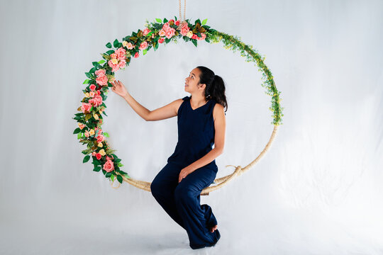 Mulher sentada em arco de flores para ensaio fotográfico em estúdio
